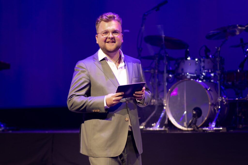 Marijn Jansen lachend op het podium als dagvoorzitter