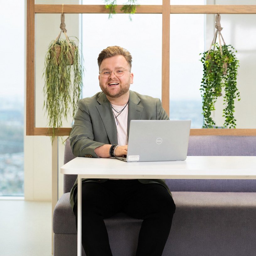 Marijn Jansen lachend achter zijn laptop tussen hangplanten